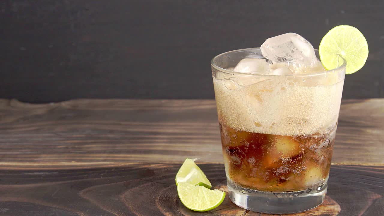 vaso de 4k con rodaja de limón y cubo de hielo vertido con coca cola - foto de estudio