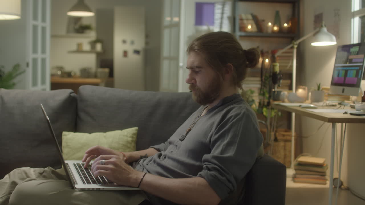 Man Typing on Laptop on Sofa at Home