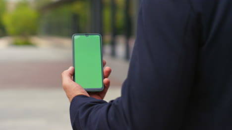 closeup hand use green screen smartphone on street. man in suit talking call