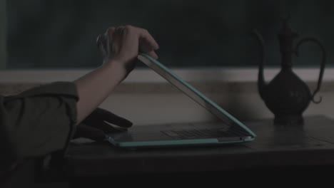 feminine, delicate hands open and type on a laptop in low light