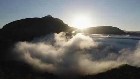 drone view above the clouds with the mountains in the distance and the sunrise