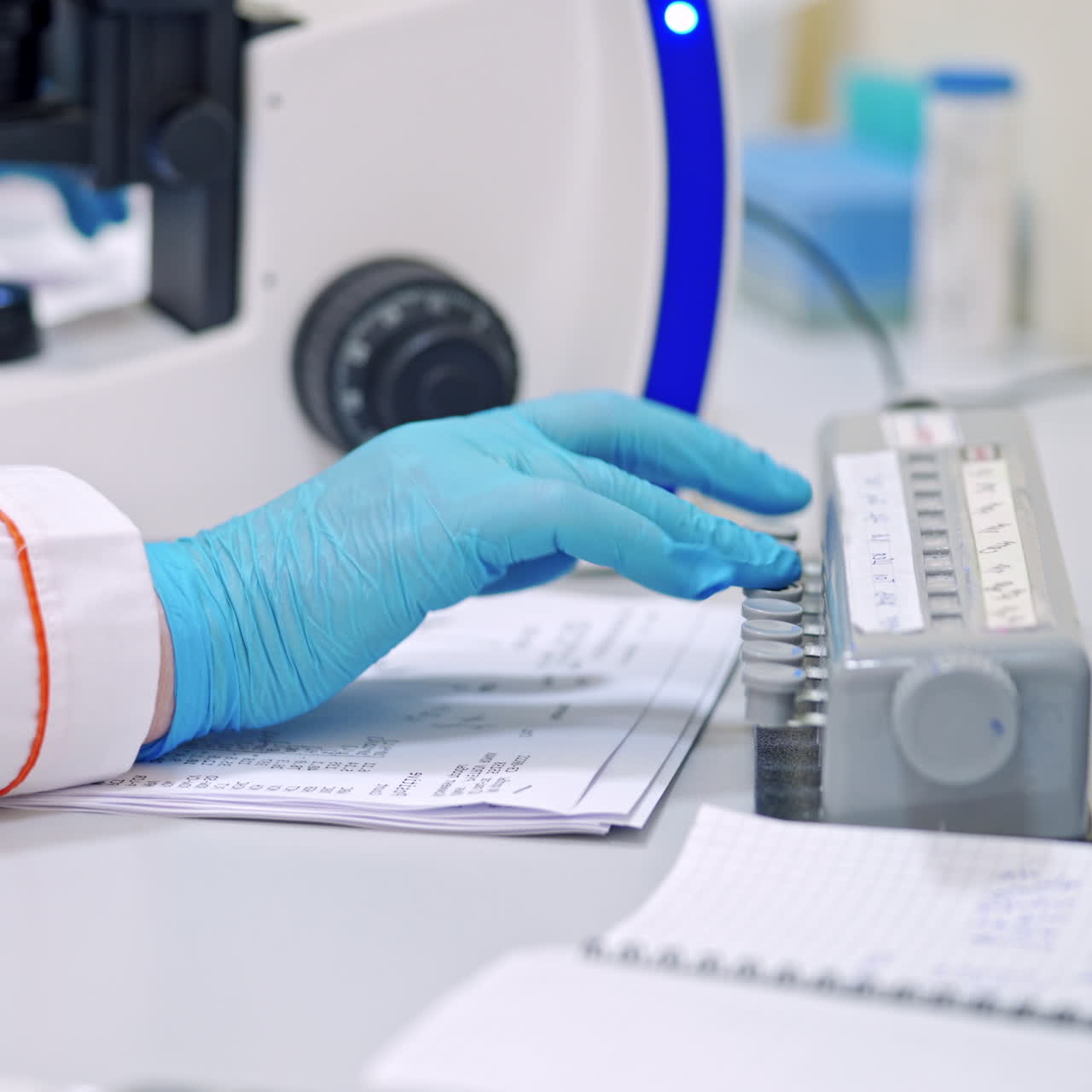 Hands in blue gloves of medical worker. Laboratory scientist works with microscope on thetable. Close-up.