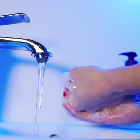 woman washing hands with soap over sink in bathroom, closeup