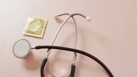 Video-of-close-up-of-stethoscope-with-condom-on-pink-background