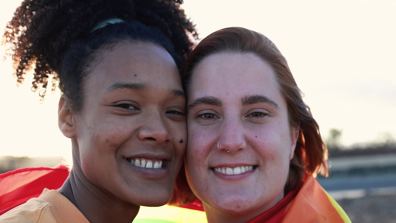 una pareja de lesbianas multirraciales sonriendo a la cámara al aire libre