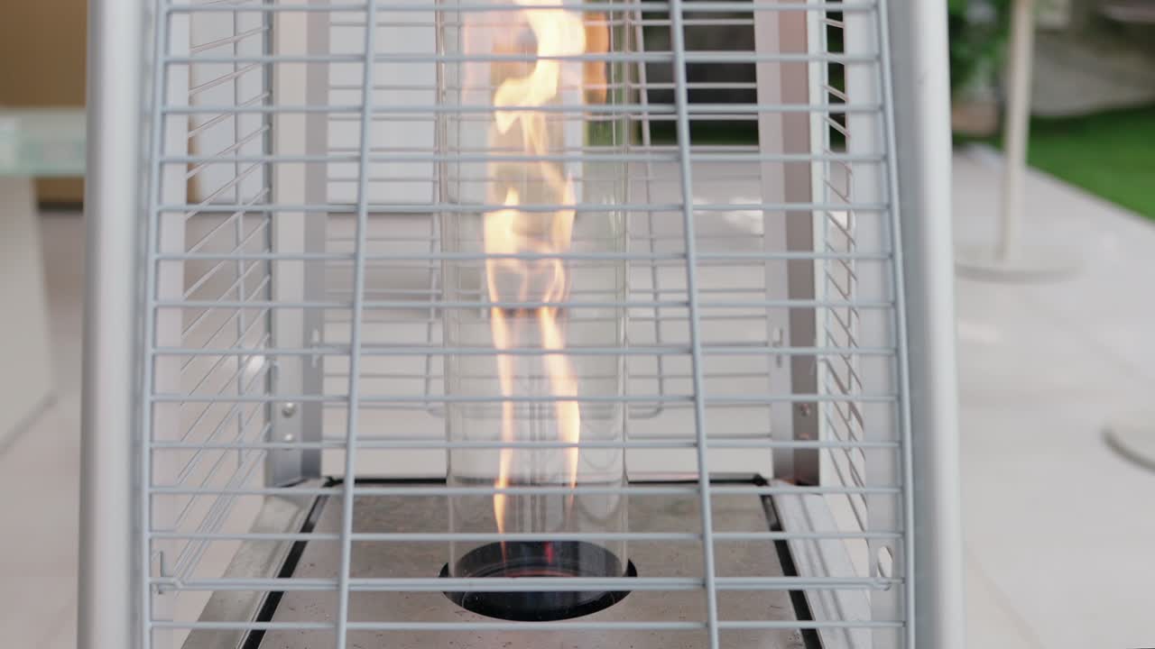 Vertical patio heater with visible flame behind metal grid in outdoor space