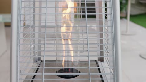 vertical patio heater with visible flame behind metal grid in outdoor space