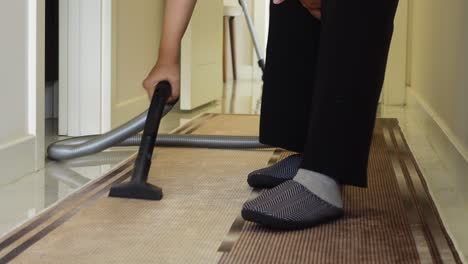 a woman vacuuming a carpet in a hallway