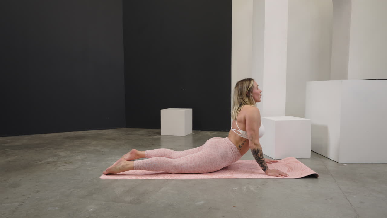 Fitness routine of a woman performing core workouts with focused determination as she stretches in cobra position into childs pose