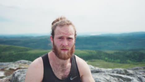 bearded man with pony-tailed hair outdoor on a sunny day in norwegian countryside