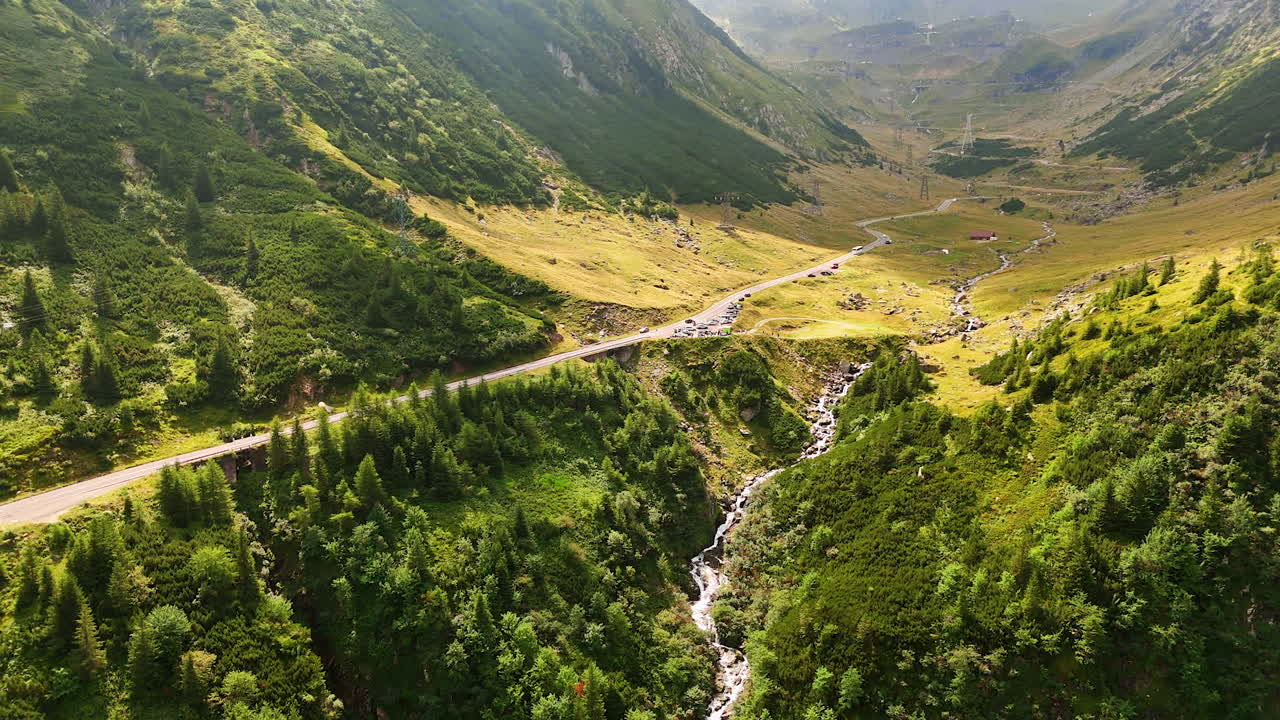 Outstanding beauty of the Carpathian Mountains from drone. Transport rides by the road along the stream flowing in the valley