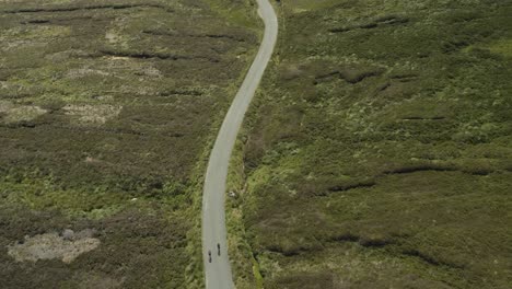 two cyclists riding along the extremely narrow roads of the wicklow mountains in ireland - tracking shot