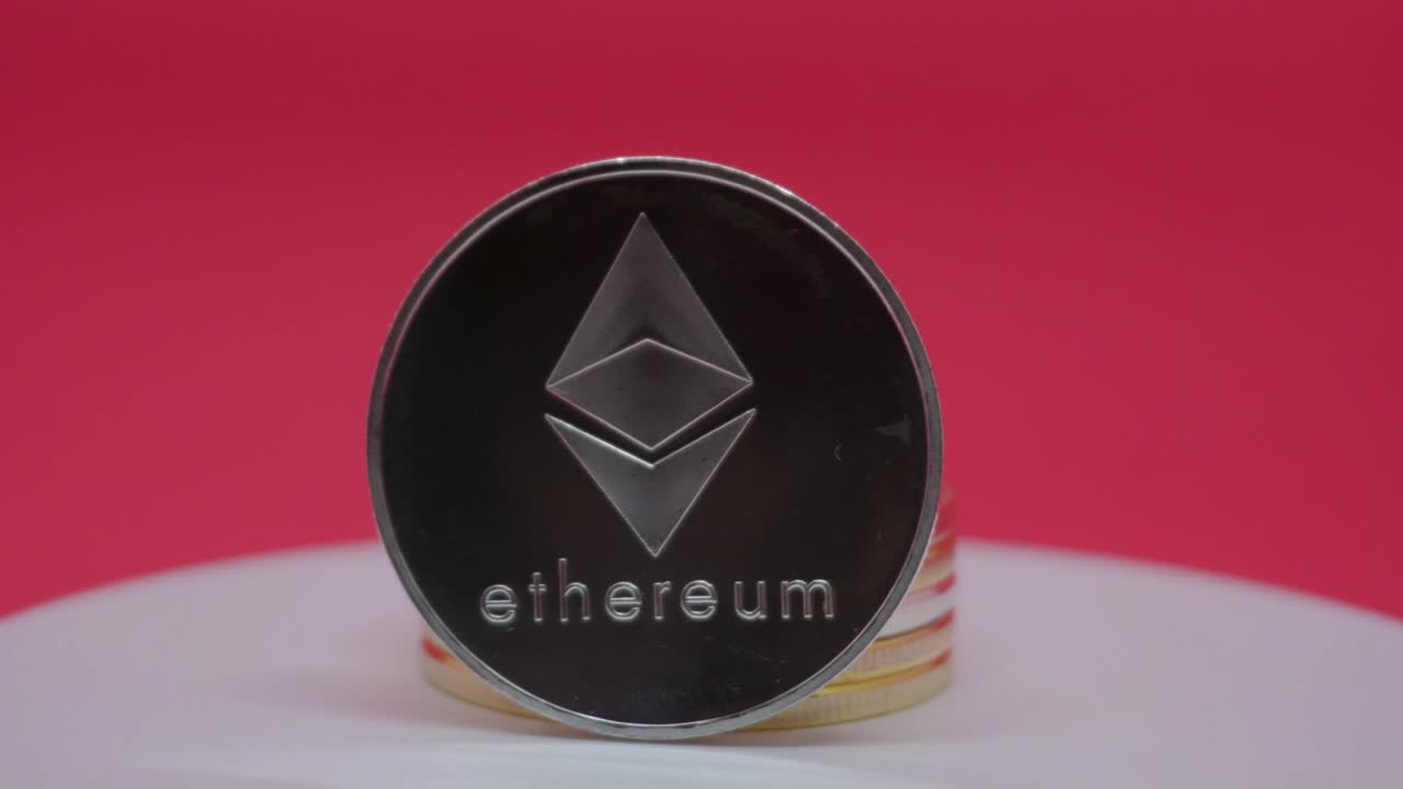 Ethereum (ETH) cryptocurrency price goes down - metal Ethereum coin is spinning in front of the red background.