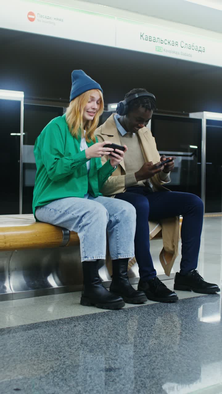 People sitting on a bench playing on their phones