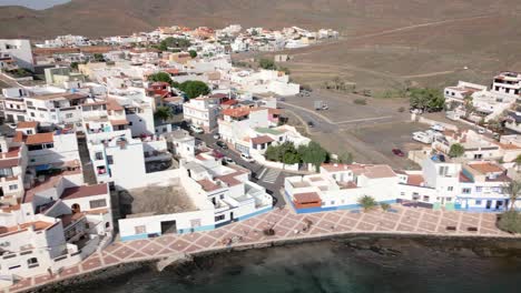 Hermosas-Villas-Blancas-Con-Rayas-Azules-En-La-Ladera-Se-Revelan-Mientras-El-Dron-Continúa-Un-Movimiento-De-Carro-Hacia-La-Izquierda