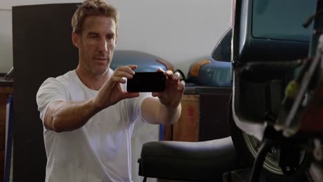 male mechanic taking photo of motorbike in repair garage 4k