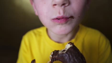 el rubio disfruta de los dulces, el niño feliz come una rosquilla de azúcar, el niño come comida chatarra.
