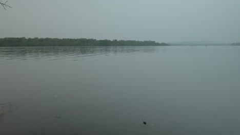 Ruhige-Flussfläche-In-Der-Abenddämmerung,-Heitere-Landschaft-Mit-Sanftem-Wasser-Und-Bewölktem-Himmel