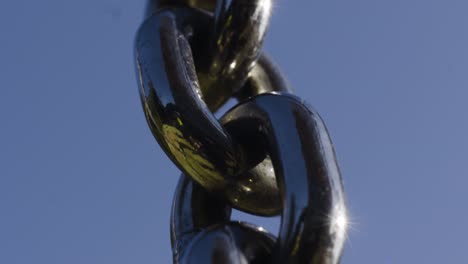 close-up view of metal chain against a clear blue sky