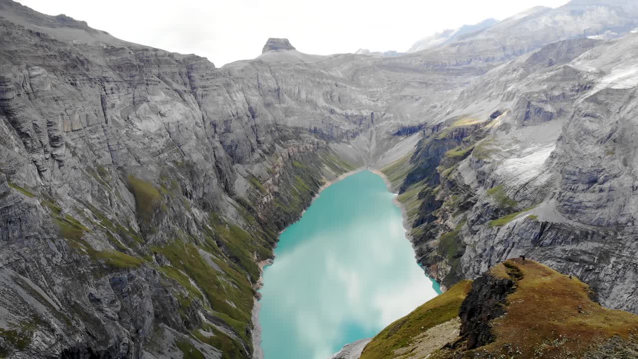 un paso elevado sobre un mirador del lago limernsee en glarus, suiza, con excursionistas disfrutando de la vista de los acantilados de los alpes suizos, el paisaje y el agua turquesa