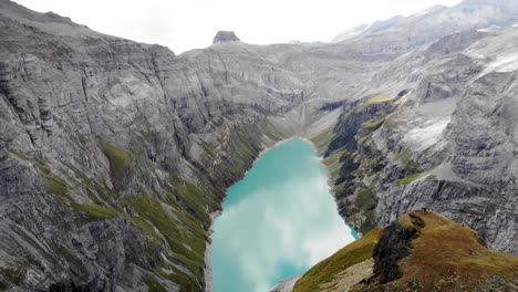 a flyover above a viewpoint of lake limmernsee in glarus, switzerland, with hikers enjoying the view of the swiss alps cliffs, landscape and turquoise water