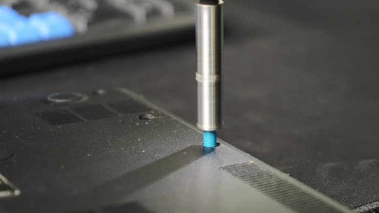 Repair of an old laptop, the technician disassembles the casing, close-up on a screw