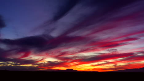 la luz del amanecer llena el cielo con nubes coloridas con el paisaje del desierto de mojave en silueta - gran angular, zoom lento