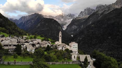 Sobrevuelo-Aéreo-Sobre-El-Histórico-Pueblo-De-Soglio-En-La-Región-De-Bregaglia-De-Grissons,-Suiza-Con-Vistas-A-La-Antigua-Iglesia-Y-Los-Picos-Montañosos-De-Engadin