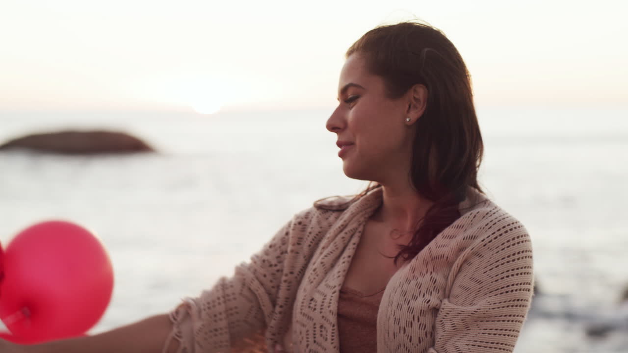 mujer disfrutando de una puesta de sol en la playa con globos