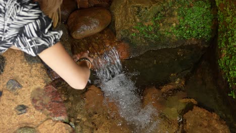 thirsty person drinking refreshing water from spring in cave, handheld