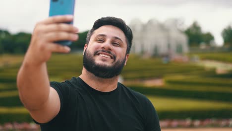 handsome young man smiling while taking a selfie at a park outdoors located at botanical garden, curitiba, brazil
