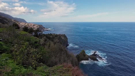 Island-view-over-the-ocean-and-the-sea,-with-the-cliffs-on-the-side-and-the-water-crashing-onto-the-cliffs-and-a-very-calming-sea