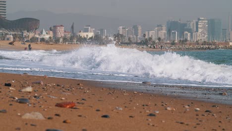 60FPS:-Waves-crash-on-beach-in-Barcelona-with-a-beautiful-skyline-in-the-background---mid-shot