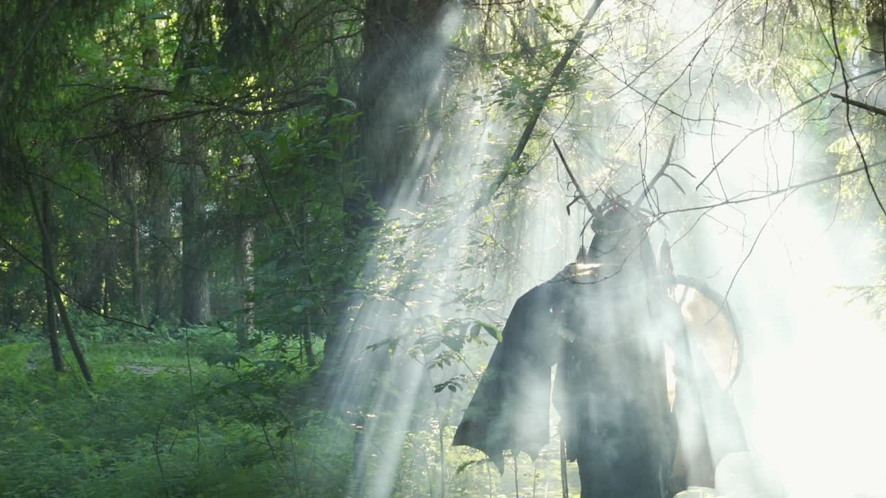 шаман ходит в лучах солнца и играет на барабане