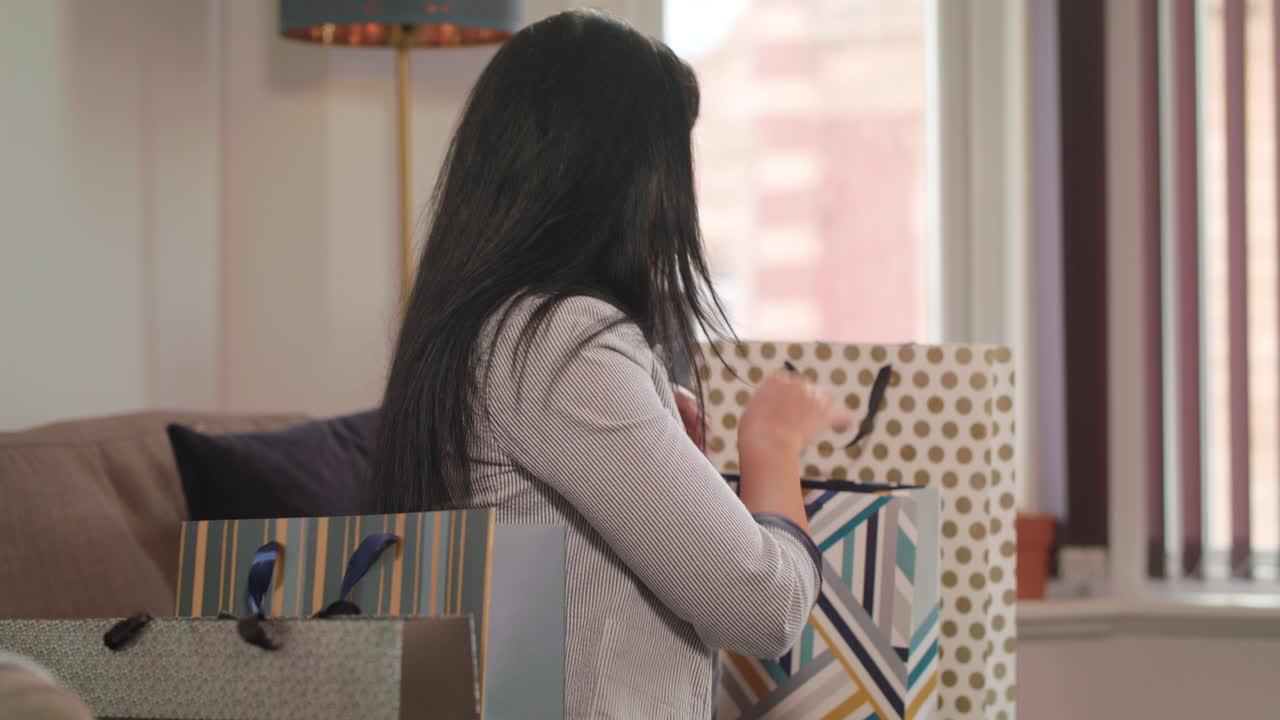 젊은 여성은 쇼핑 여행 후 최근 구매한 물건을 행복하게 살펴봅니다.