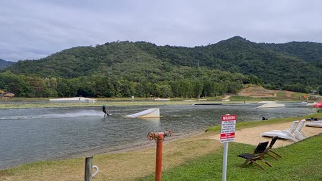 adult being pulled by rope and jumping ramp at wakeboarding park