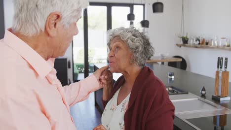 happy senior diverse couple dancing in kitchen at retirement home