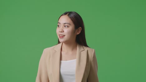 woman in beige business suit smiling on green screen