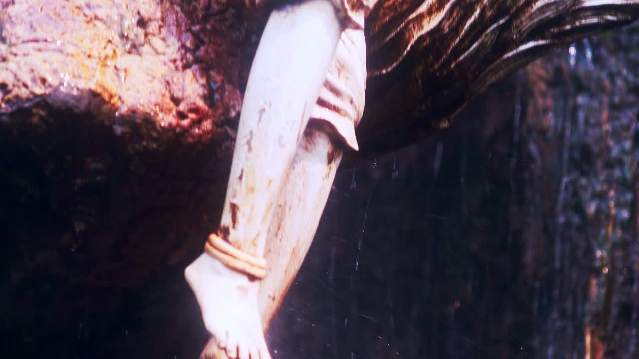 열린 팔로 앉아 있는 천사의 동상 위에 떨어지는 폭포