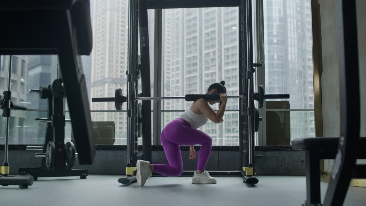 젊은 여성이 체육관에서 허리 스을 하고, 체력을 유지하고, 전체 몸 운동을 합니다.