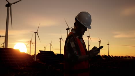 engineer working at wind and solar farm at sunset