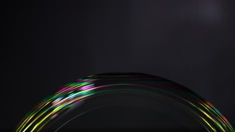a soap bubble displays vibrant color reflections against a dark background, showcasing light interaction and surface tension