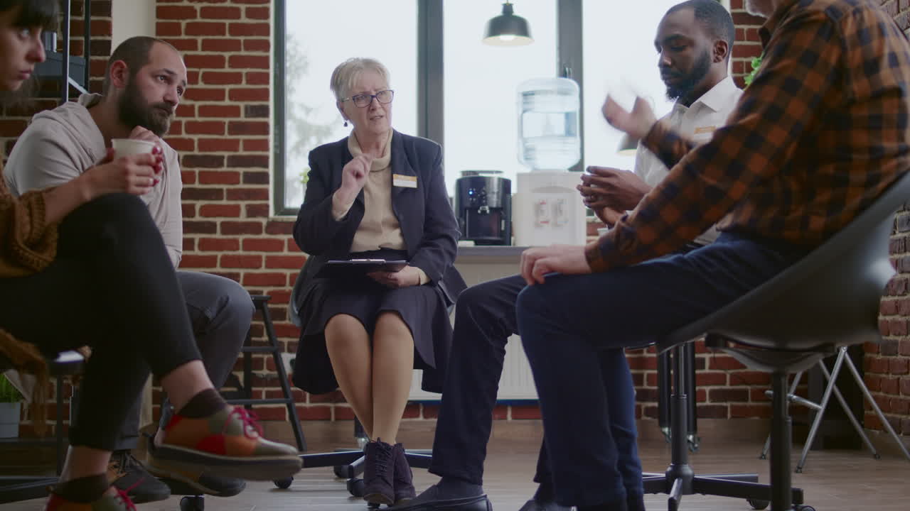 Psychologist having conversation with people in circle at aa group therapy session