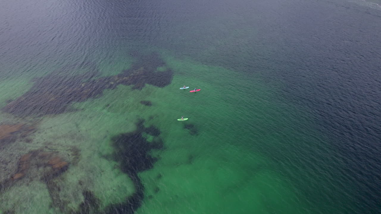 스탠드업 패들 보드에 있는 로포텐 섬의 경치 좋은 리네피오르덴에서 노를 젓는 관광객의 슬라이딩 샷