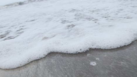agua de mar espumosa lavándose en una playa de arena a cámara lenta