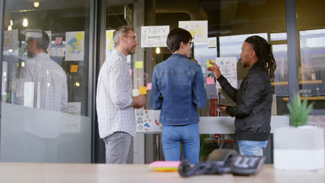 Business-people-discussing-over-sticky-notes-in-office-4k