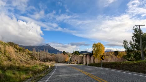a vehicle travels a winding country road through autumn fields and hills, with vibrant foliage, open skies, and dynamic forward camera movement in daylight