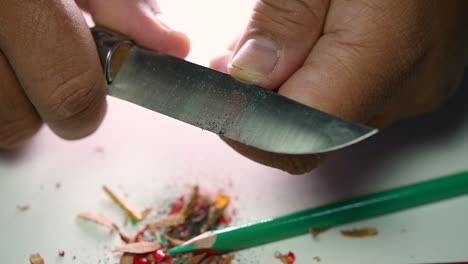 Footage-of-hands-slowly-sharpening-a-pencil-and-some-coloured-pencils-with-a-sharp-knife