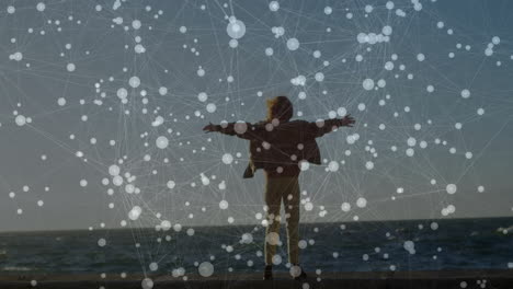 woman standing on pier overlooking sea, with animated network overlay showing technology connection