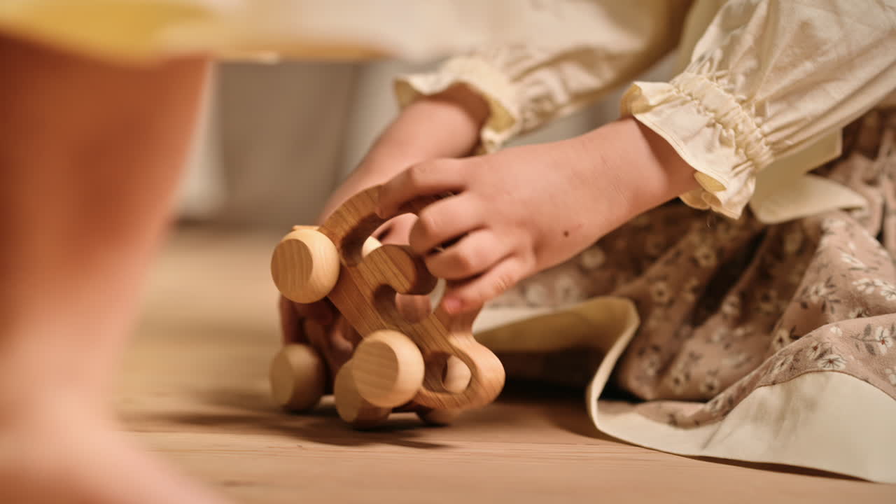 Two little girls playing with wooden snail rolling toys on the floor. Ecological and sustainability concept